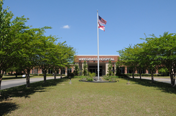 Photo of the entrance to Wiregrass Hospital with a flag pole holding the American Flag as well as the Alabama State Flag
