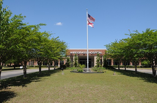 Photo of the entrance to Wiregrass Hospital with a flag pole out front containing the American Flag as well as the Alabama State flag