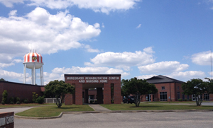 Photo of the entrance to Wiregrass Rehabilitation Center with red and white striped water tower in the background