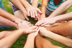 A photo of a group of people stacking their hands on top of each other in a circle