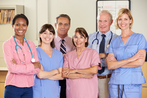 A group of male and female doctors and nurses standing with their arms crossed and smiling