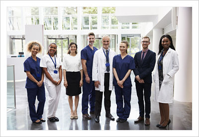 A group of people dressed in lab coats, scrubs, and professional apparel standing together for a photo